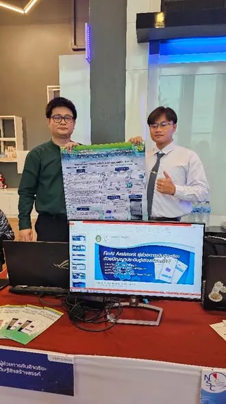 Charnsak Srisawatsakul stands with a student beside the FinAI Assistant project exhibit at the National Software Contest